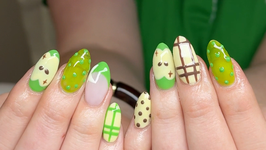 Hand painted character nail art in greens and yellows across both hands