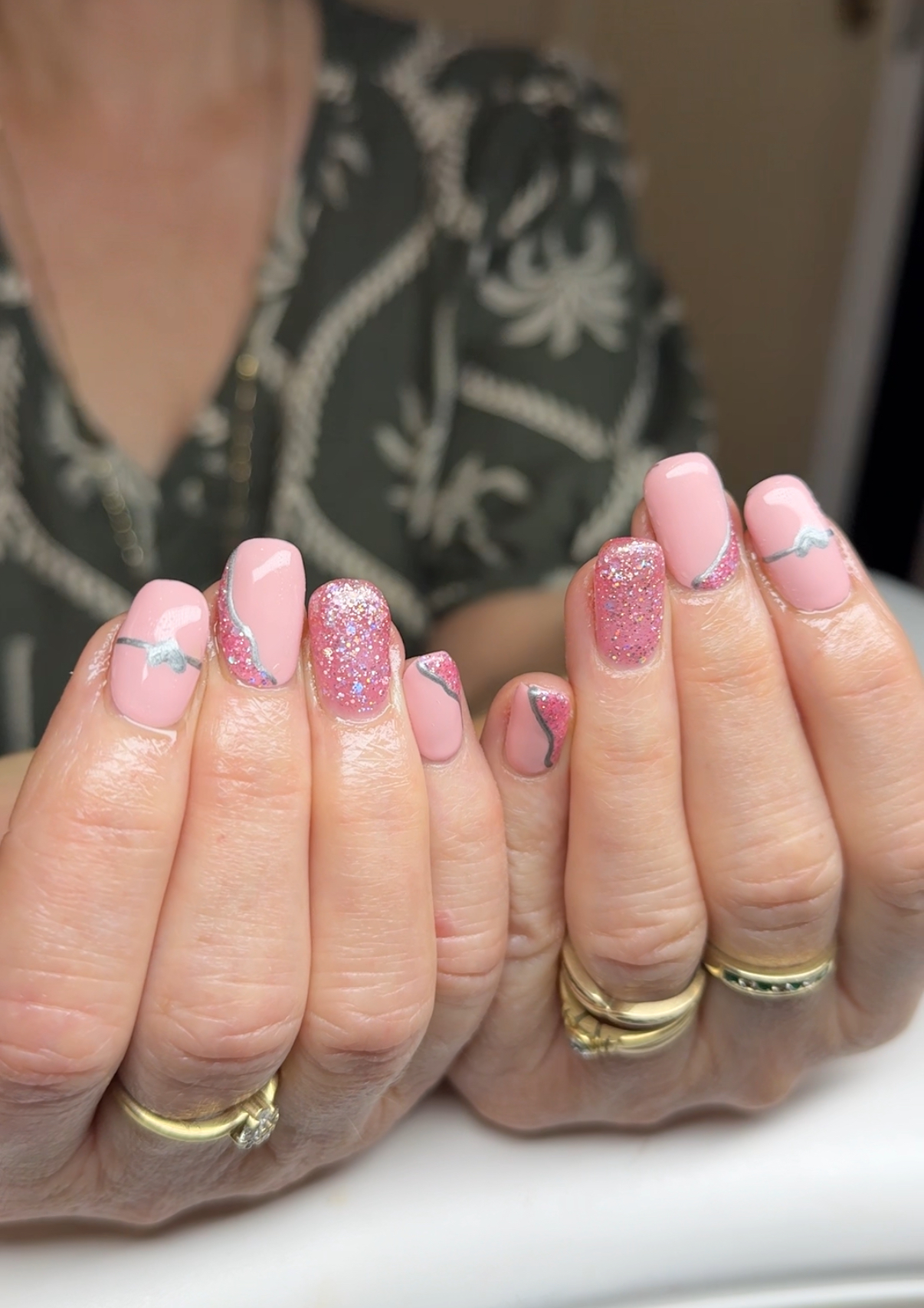 Pink gel nails with silver swirl line art and glitter accents