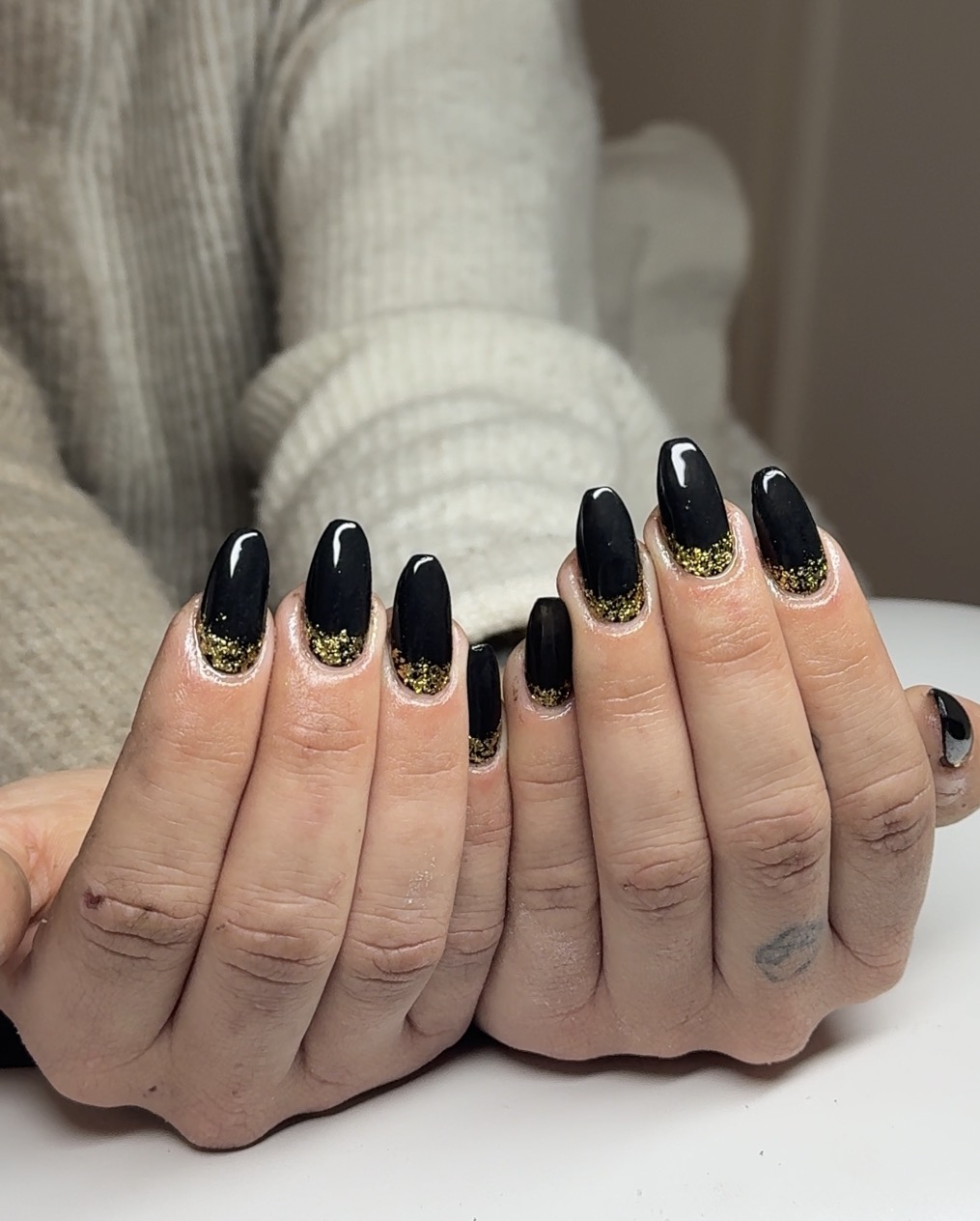 Black almond gel nails with a gold glitter cuticle fade