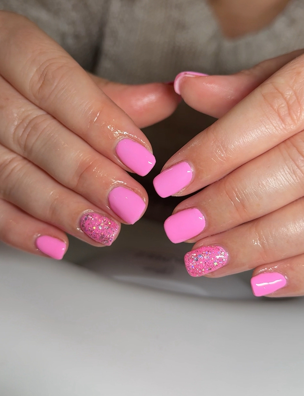 Bright pink gel nails with two glitter accent nails